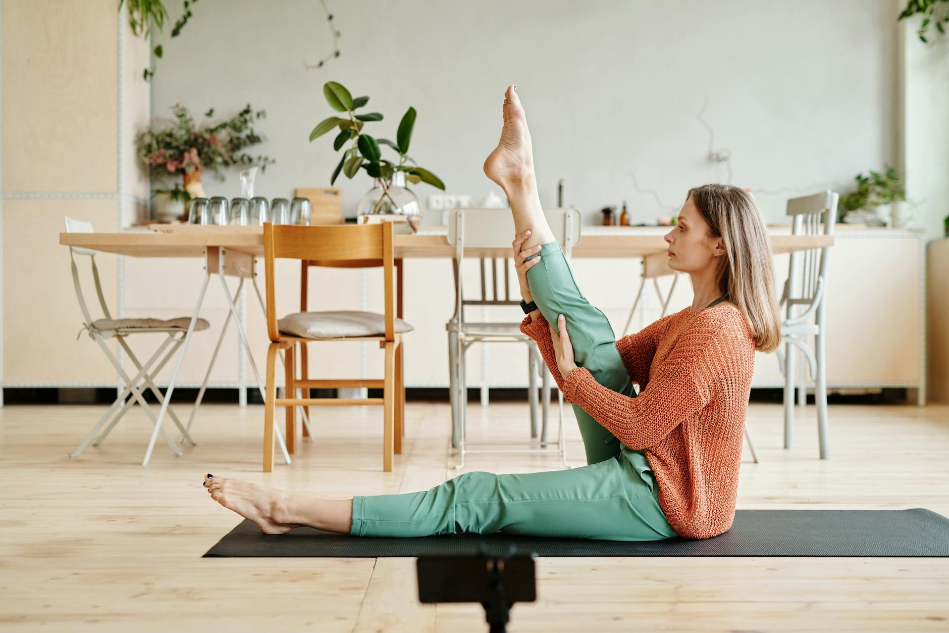 Kobieta wykonuje krótki stretching jogi w salonie wśród roślin