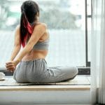 Poranna mobilizacja kręgosłupa w 10 minut Kobieta na macie porannie rozciąga plecy na tarasie