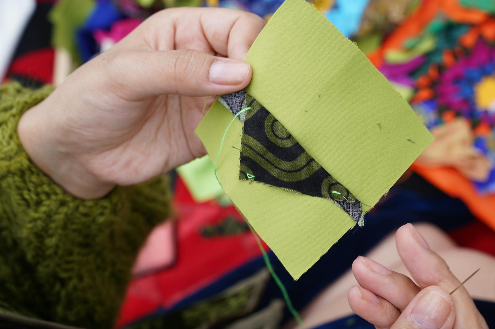 Dłonie szyjące patchwork z kolorowych tkanin tradycyjną techniką quiltingu