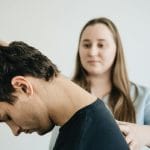 Fizjoterapeuta wykonuje z pacjentem ćwiczenia szyi w gabinecie