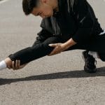 Młody mężczyzna rozciąga biodra, ćwicząc na miejskim chodniku