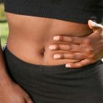 Osoba na zewnątrz trzymająca bolesny brzuch po zabiegu w jamie brzusznej