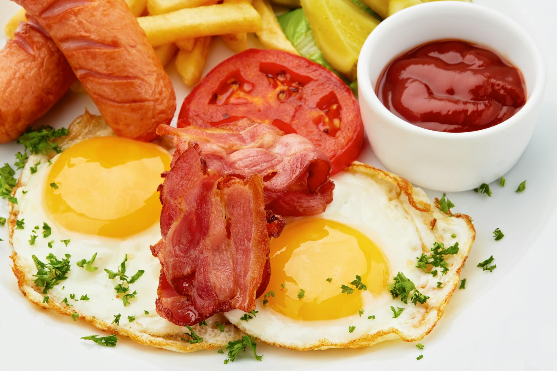 Śniadanie z jajkami sadzonymi, bekonem, kiełbaskami i warzywami