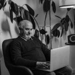 Starszy mężczyzna pracuje przy laptopie w wygodnym fotelu