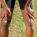 Zmęczony sportowiec na dworze trzyma kolana po intensywnym treningu