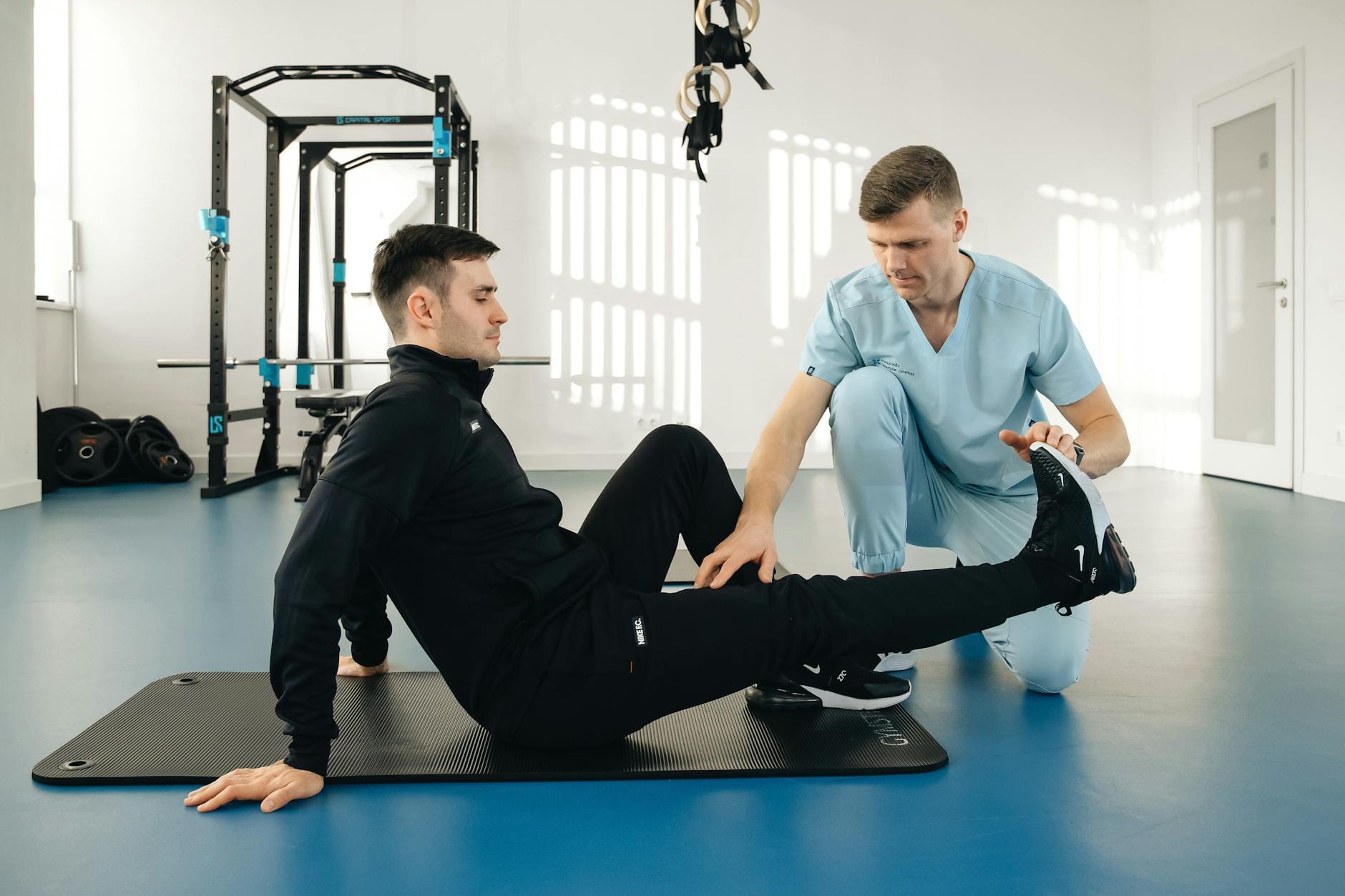 Fizjoterapeuta pomaga mężczyźnie ćwiczyć podczas rehabilitacji w klinice
