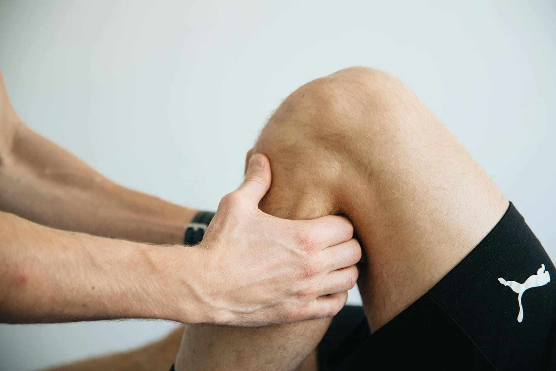 Fizjoterapeuta wykonuje masaż kolana pacjenta po zabiegu menisku