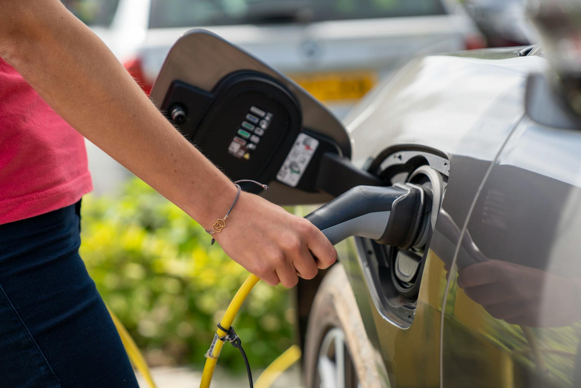 Kierowca podłącza samochód elektryczny do ładowarki na zewnątrz Kierowca podłącza samochód elektryczny do ładowarki na zewnątrz