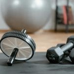 Core w domu bez podskoków: trening stabilizacji przy wrażliwych stawach Kółko do ćwiczeń i hantle na macie w domowej siłowni