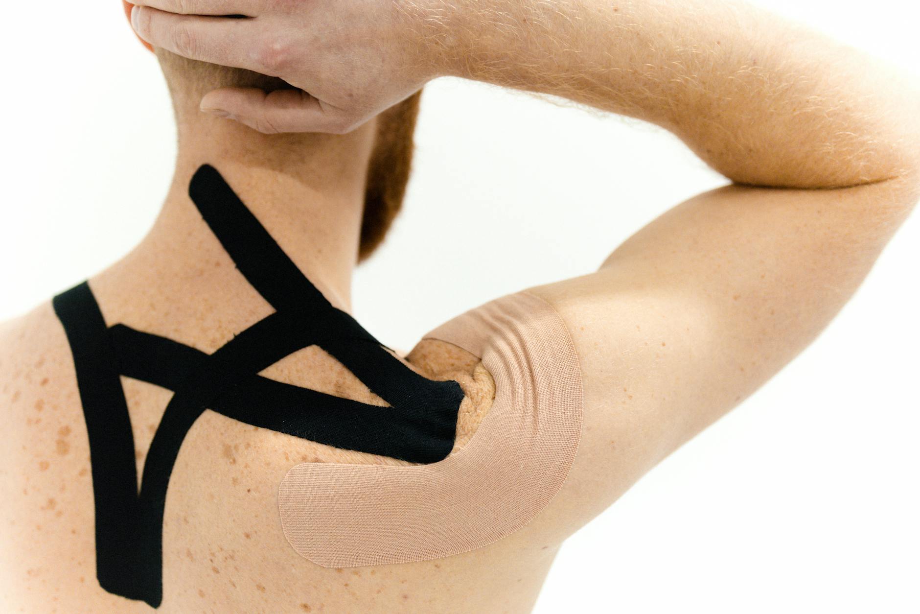 Mężczyzna z plastrem kinesiotaping na barku jako przykład terapii bólu