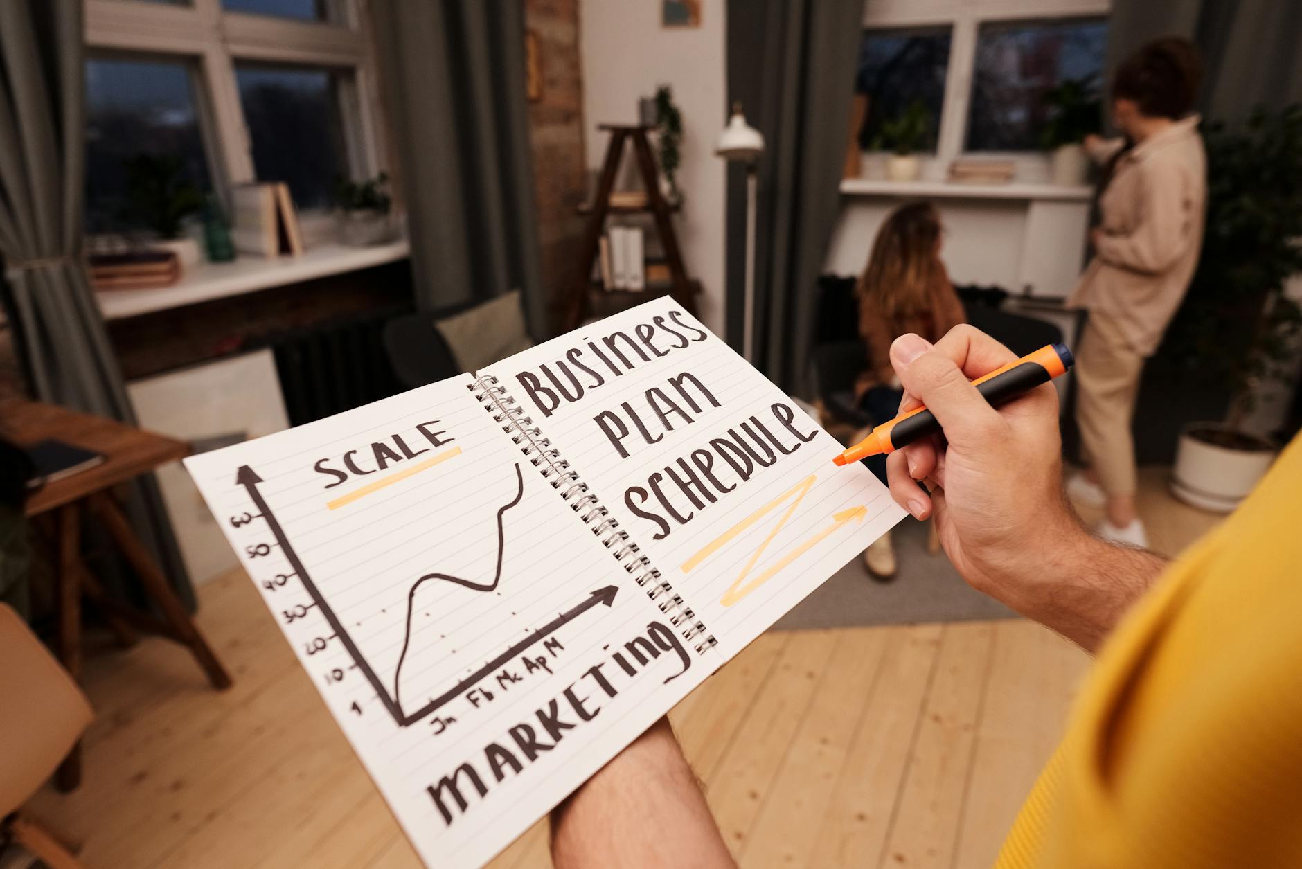 Osoba trzyma notes z planem biznesowym i wykresem strategii