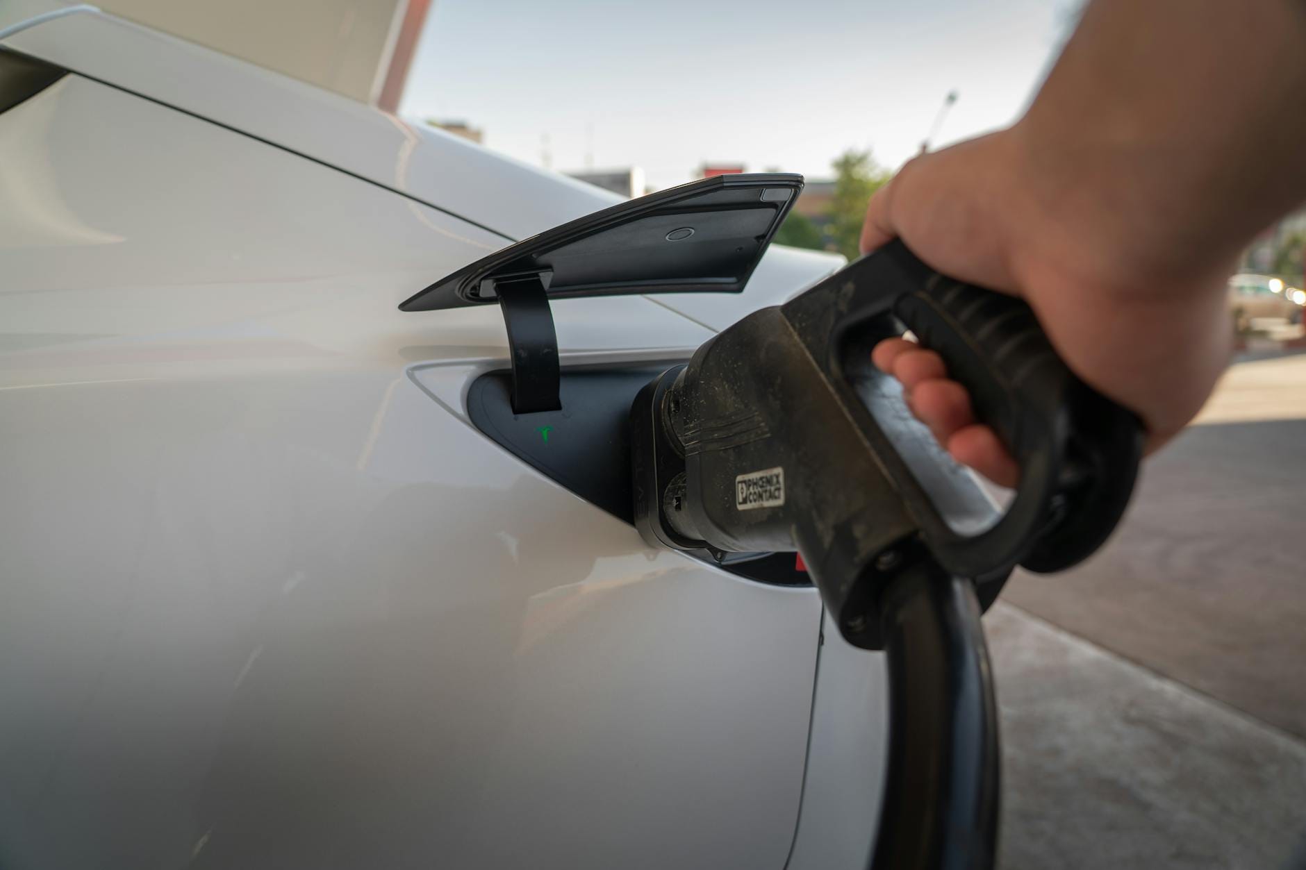 Zbliżenie na ładowany samochód elektryczny przy publicznej ładowarce