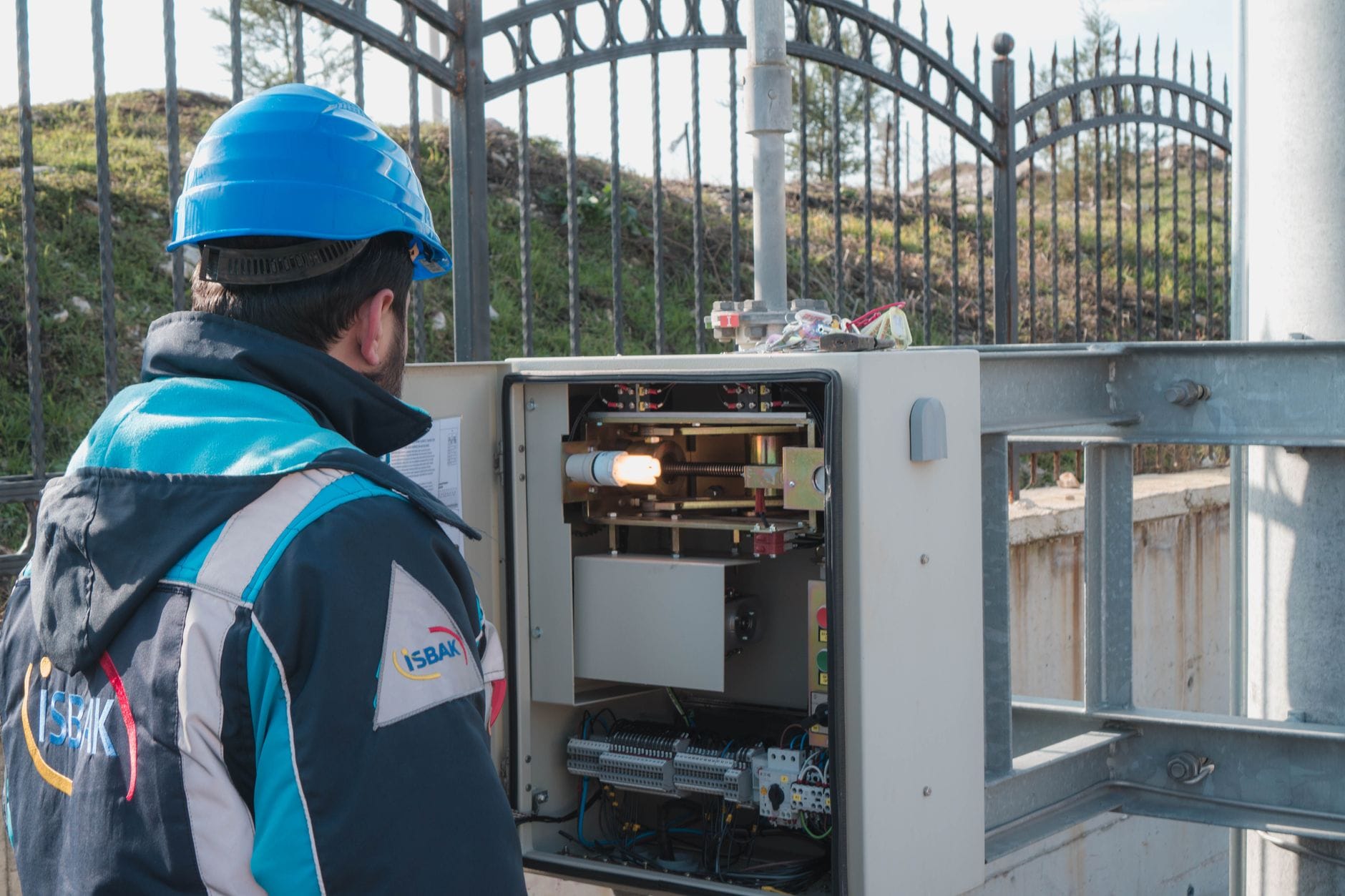Elektryk w kasku sprawdza zewnętrzną skrzynkę z bezpiecznikami