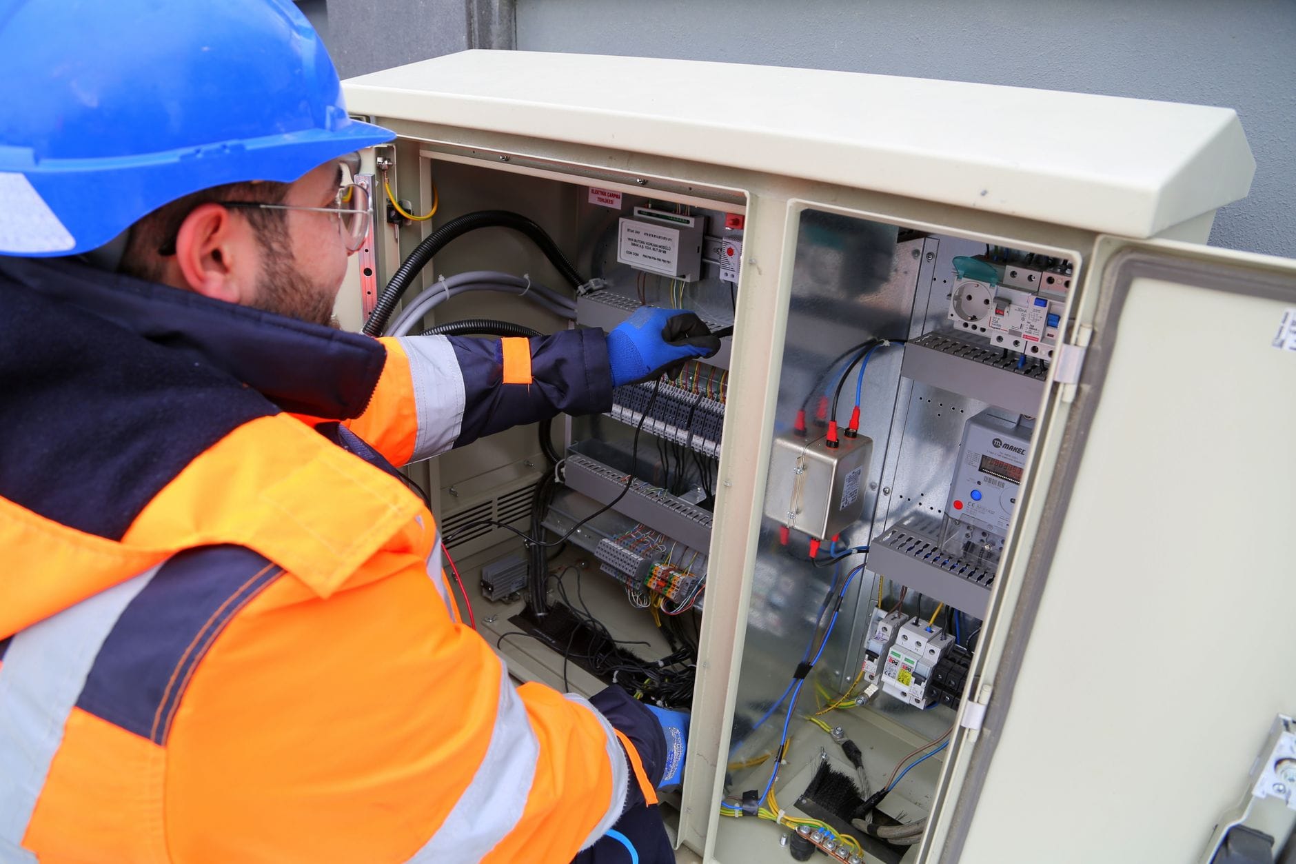 Inżynier w kasku sprawdza zewnętrzną rozdzielnicę elektryczną Inżynier w kasku sprawdza zewnętrzną rozdzielnicę elektryczną