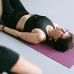 Kręgosłup i oddychanie: proste ćwiczenia przeponą na napięcie w plecach Kobieta w stroju sportowym relaksuje na macie do jogi w domu