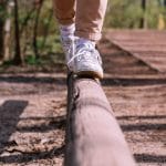 Stopy osoby idącej po drewnianej belce w parku, trening równowagi