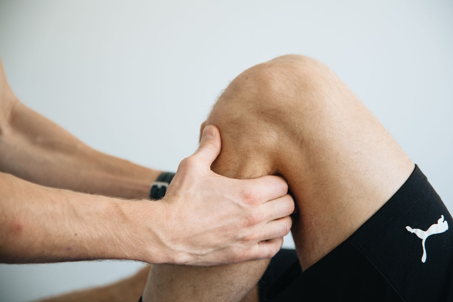 Fizjoterapeuta masuje kolano podczas rehabilitacji po endoprotezie