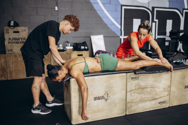 Sportowiec podczas terapii bańkami w siłowni z dwoma terapeutami